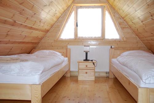 2 camas num quarto de madeira com uma janela em Gościniec Nad Bukówką em Lubawka
