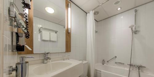 Fletcher Hotel-Restaurant Klein Zwitserland في هيلسوم: حمام مع حوض ومغسلة ومرآة