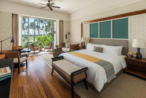 a bedroom with a large bed and a living room at Shangri-La Hambantota in Hambantota