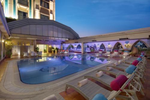 Lefkosa TurkにあるMerit Lefkosa Hotel & Casinoのホテル内のプールとその周りに椅子があります。