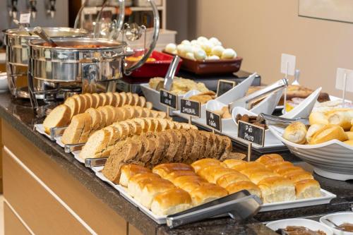 a buffet with various types of bread and pastries at Hotel Negrini in Balneário Camboriú