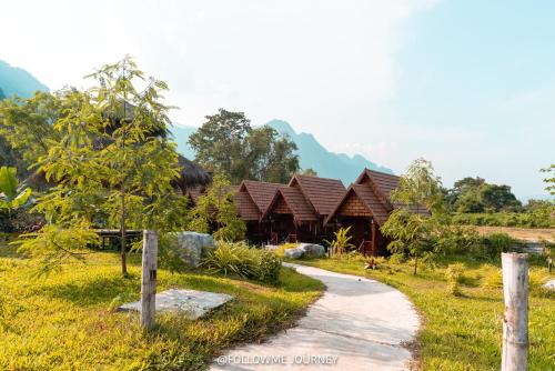 a path leading to a resort with mountains in the background at Champathong Garden Resort in Vang Vieng