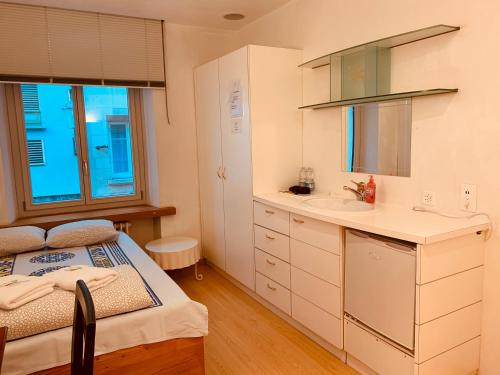 Habitación pequeña con cama y lavamanos en Swiss Dewa, en Lucerna