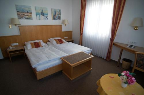 a hotel room with a bed and a table at Hotel Garni Lehrertal in Ulm