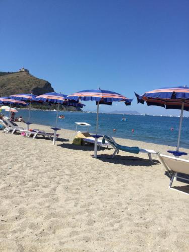 a beach with umbrellas and chairs and the ocean at Basicò un balcone sul mare - Casa SALITA FOTI -Case vacanza Sicilia&Toscana- in Basicò