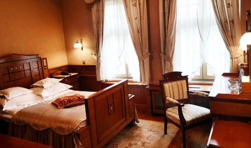 a bedroom with a bed and a chair and windows at Pałac Czarny Las (50 km od Katowic) in Woźniki