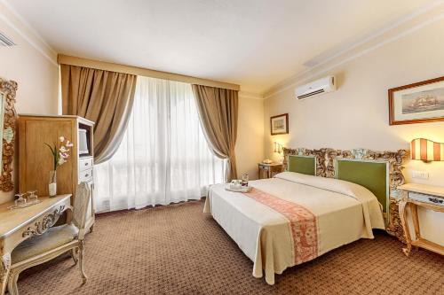 a hotel room with a bed and a window at Colonna Palace Hotel Mediterraneo in Olbia