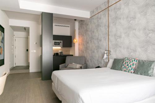 a bedroom with a large white bed and a chair at Teatro Romano 3 & 6 in M&aacute;laga