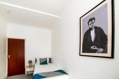 un dormitorio con una foto de un hombre en la pared en St George's Hotel, en Londres
