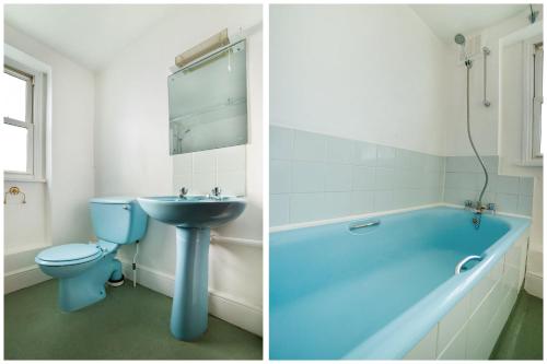 y baño con bañera azul, aseo y lavamanos. en St George's Hotel, en Londres
