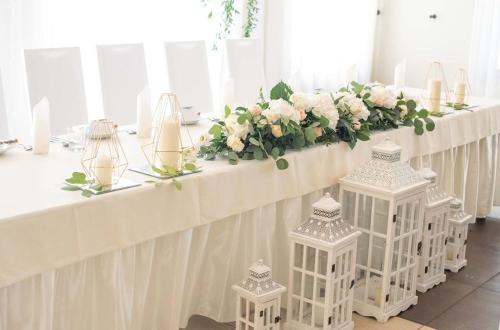a row of white tables with flowers and candles at Hotel Słoneczny Brzeg in Biskupiec