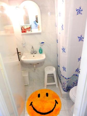 a bathroom with a smiley face rug on the floor at Maria Studios in Ayia Evfimia