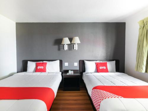two beds in a room with red and white at OYO Hotel Irving DFW Airport North in Irving