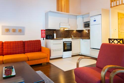 a living room with two orange chairs and a kitchen at Kolin Lotus Cottages in Kolinkylä