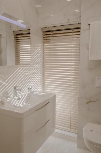 a white bathroom with a sink and a toilet at Green House Hotel & Restaurant in Tirana
