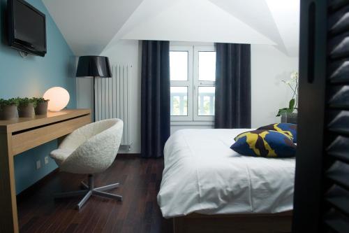 une chambre avec un lit, un bureau et une chaise dans l'établissement Hotel Du Golf, à Saint-Étienne
