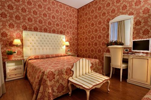 a bedroom with a bed and a chair and a desk at Locanda Casa Querini in Venice