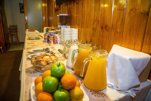 a table topped with a bowl of fruit and a glass of orange juice at Hotel Capitán Eberhard in Puerto Natales