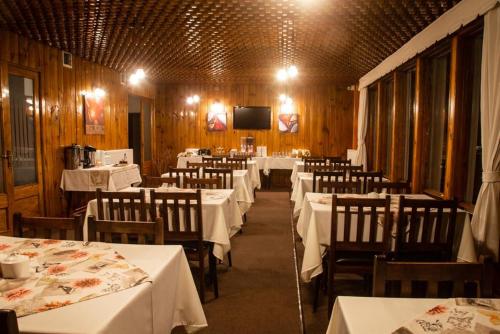 comedor con mesas y sillas blancas y TV en Hotel Capitán Eberhard, en Puerto Natales