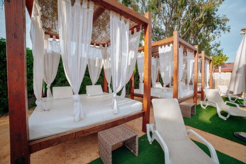 a set of four beds with white curtains and chairs at Alannia Guardamar in Guardamar del Segura
