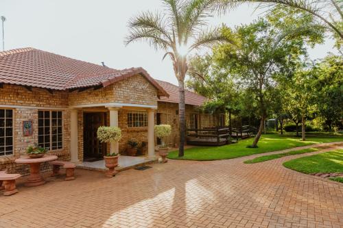 a house with a patio and a palm tree at Boubou Bed and Breakfast in Rustenburg
