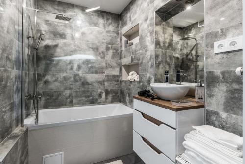 a bathroom with a white tub and a sink at Theatre Apartment - Apartament przy Rynku w Głogowie in Głogów