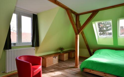 a green bedroom with a bed and a red chair at Apartment Alter Fritz in Potsdam