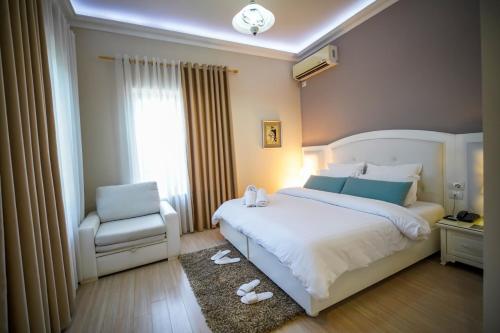 a bedroom with a white bed and a chair at Univers Resort in Elbasan