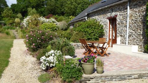 un giardino con tavolo, sedie e fiori di Kerlogan a Saint-Thois