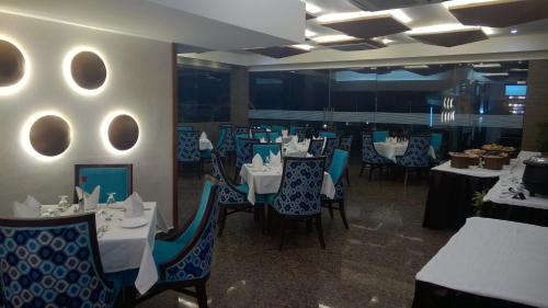 a dining room with white tables and blue chairs at Hotel Seven Hills Tower in Agra