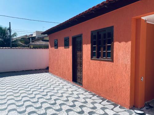 ein rotes Haus mit einer Tür und Fliesenboden in der Unterkunft Meus Guris in Arraial do Cabo