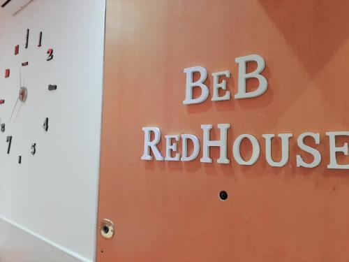 a sign that reads be red house next to a clock at Red House in Naples