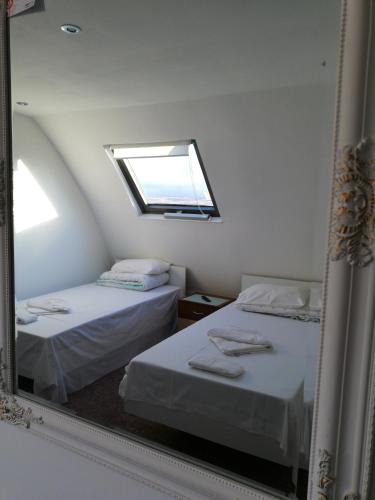 a mirror reflecting a bedroom with two beds and a window at Hotel Hobby in Hunedoara