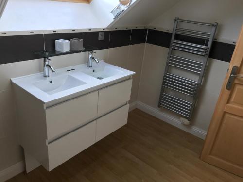 a bathroom with a white sink and a shelf at Maison Ensoleillee - in Gesnes-le-Gandelin