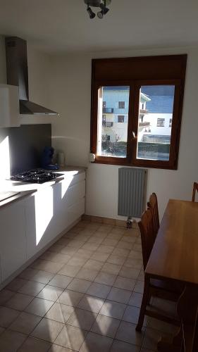 une cuisine avec une table et une cuisinière ainsi qu'une fenêtre dans l'établissement Appartement au pied des 3 Vallées, à Moutiers