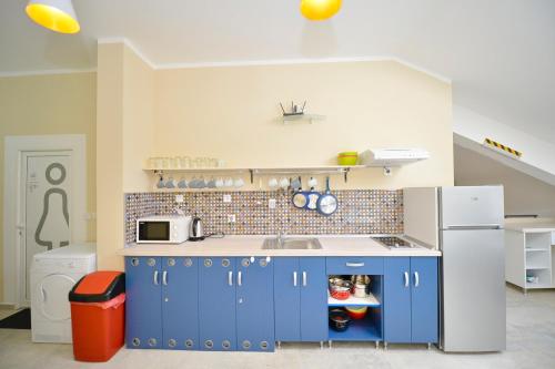 a kitchen with blue cabinets and a white refrigerator at Hostel Pupa in Kotor