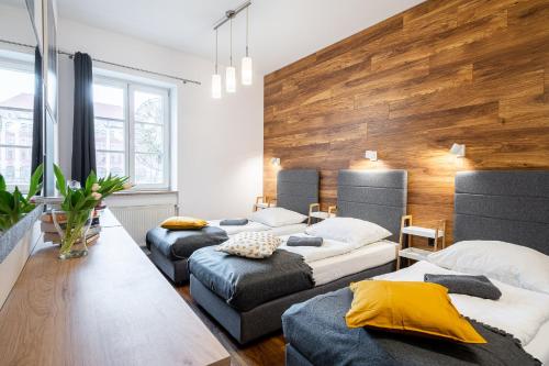 a room with four beds and a wooden wall at Solny Square Aparthotel in Wrocław