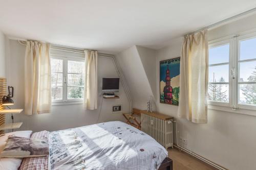 um quarto com uma cama e duas janelas em Appartement Odyssée - Welkeys em Megève