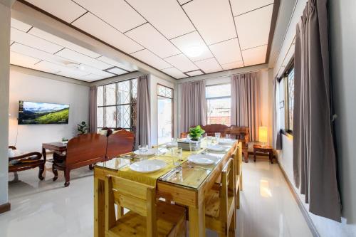 a dining room with a long table with chairs and a piano at Bluebell House Hatyai - Cosy 3 bedrooms for 10 pax - 9 mins drive to Lee Grd in Hat Yai