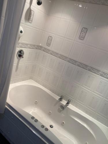 a bath tub in a bathroom with white tiles at Bessemer Hotel in Merthyr Tydfil