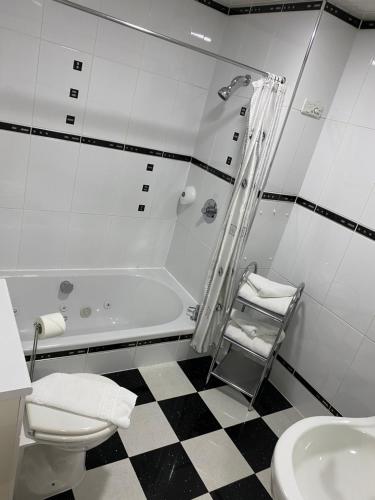 a bathroom with a tub and a toilet and a sink at Bessemer Hotel in Merthyr Tydfil