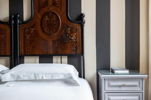 a bed with a wooden headboard next to a night stand at Casa Montani in Rome