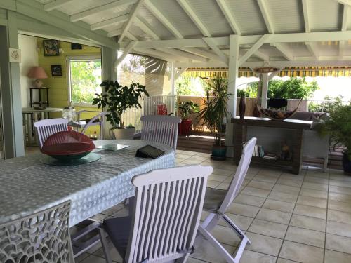 a porch with a table and white chairs and a table and chairsktop at villa piscine majoma in Sainte-Anne