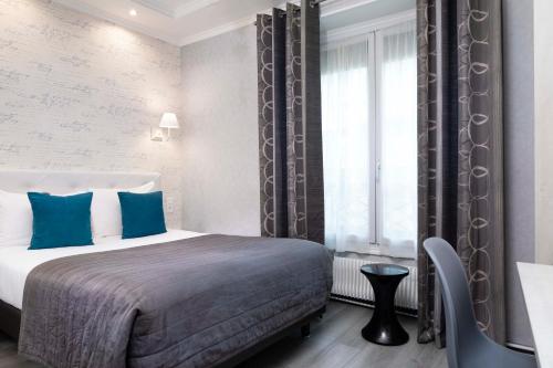 une chambre avec un lit avec des oreillers bleus et une fenêtre dans l'établissement Hôtel de Genève, à Paris