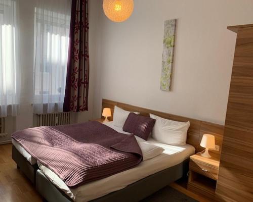 a bedroom with a bed with two lamps on it at Pension Belo Sono in Munich
