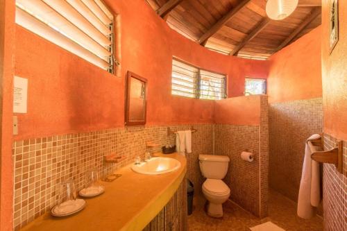 an orange bathroom with a toilet and a sink at Hotel Playa Negra in Paraíso
