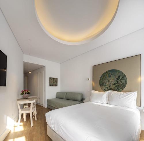 a bedroom with a large white bed and a table at Lisbon Serviced Apartments - Madalena in Lisbon
