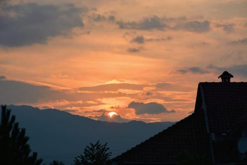 a sunset over the mountains with a house at konaku in Tomin