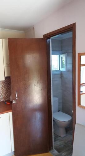 a bathroom with a toilet and a wooden door at XeniCamp & Bungalows in Tolo