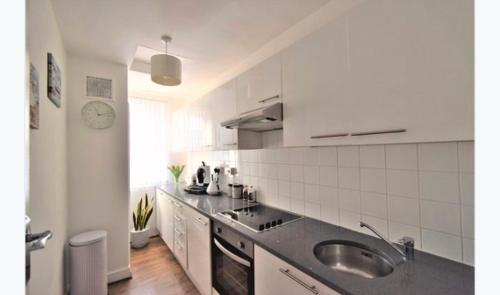 eine weiße Küche mit einer Spüle und einer Theke in der Unterkunft Super location 1min from metro 10min from Camden in London